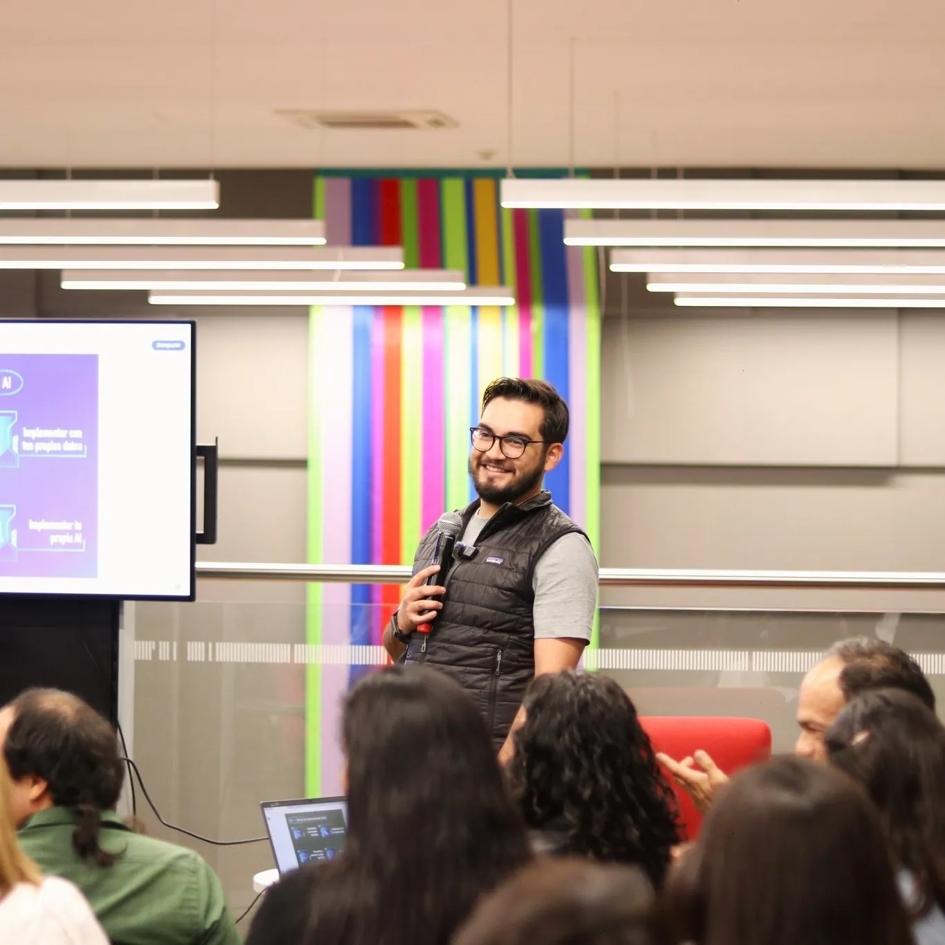 Héctor Sauza sonriendo con micrófono durante una charla frente al público