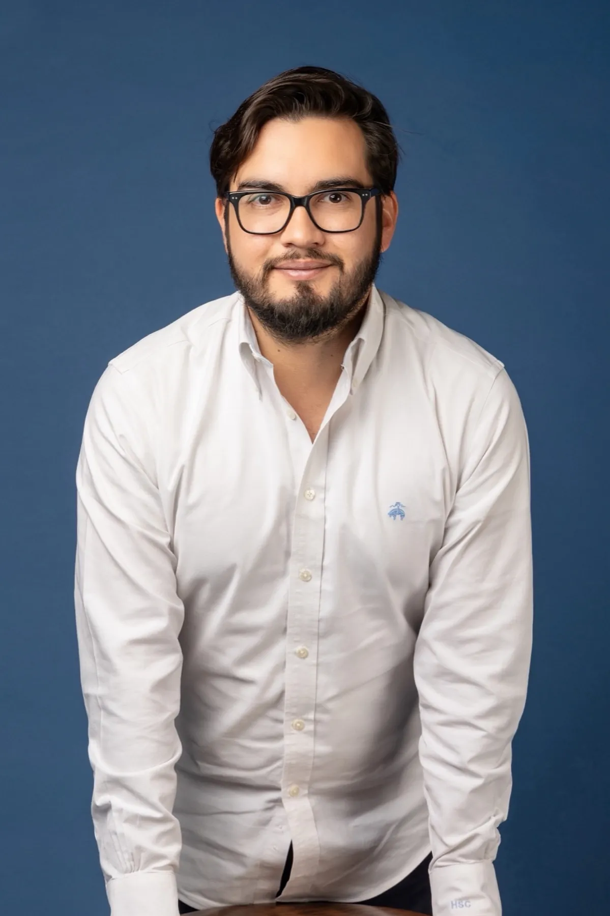 Retrato de Héctor Sauza con camisa blanca sobre fondo azul