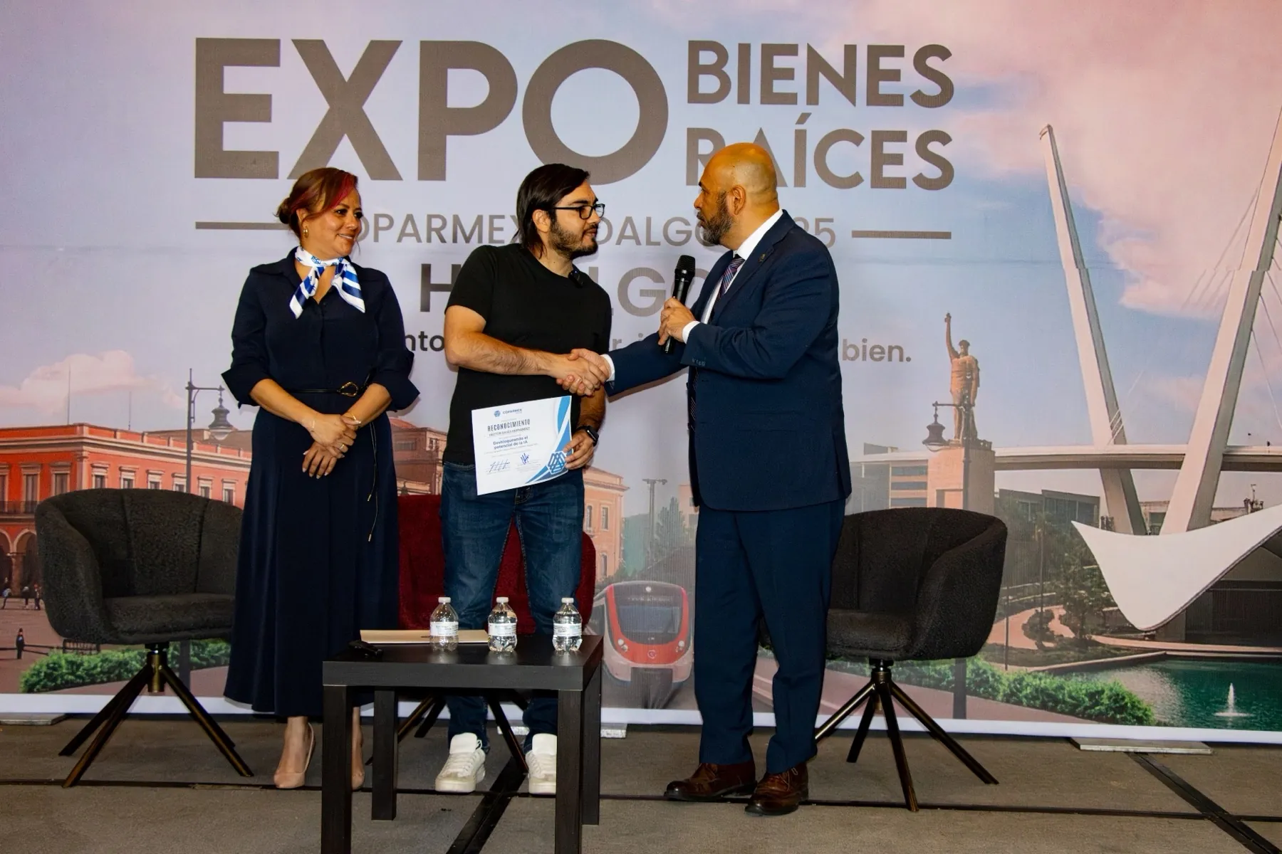 Héctor Sauza recibiendo un reconocimiento en el escenario de un evento empresarial
