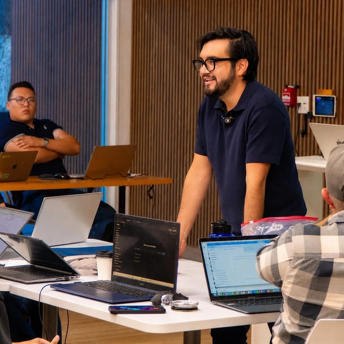 Héctor Sauza conversando con participantes durante un taller de trabajo con laptops